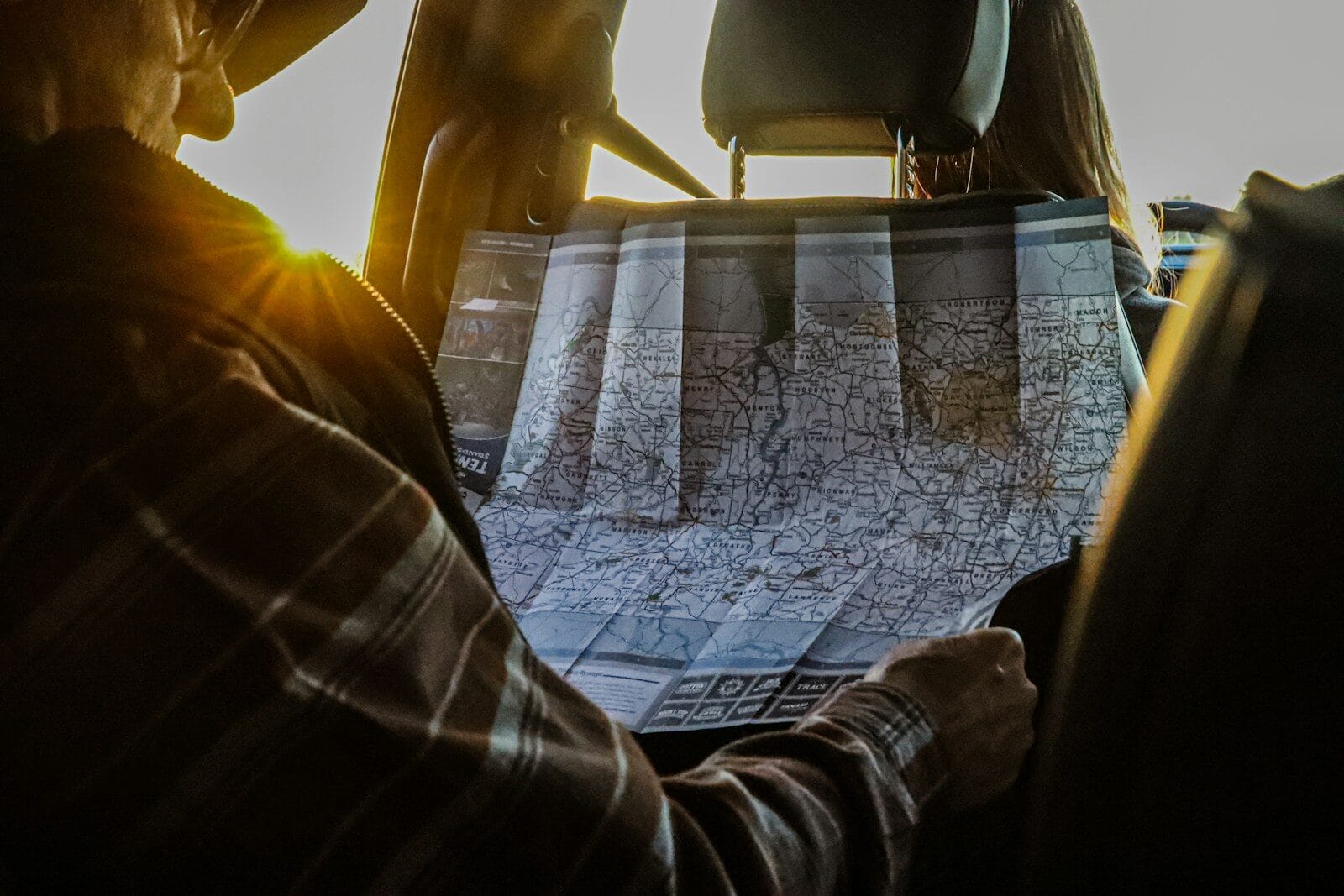 Man studying a map in a car at sunset